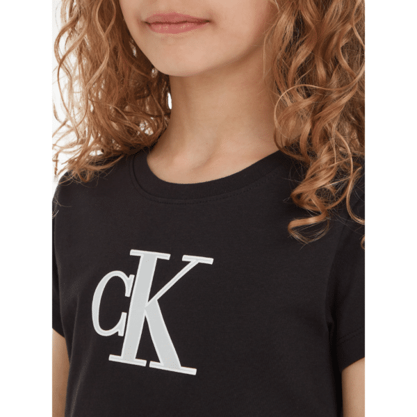calvin klein girls black tshirt with large metallic CK logo on model close up